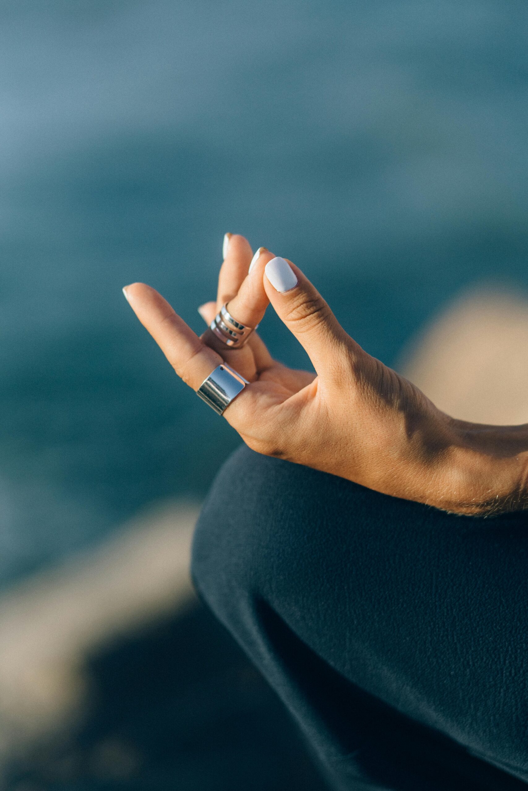 Serene close-up of a hand meditating outdoors with a blurred background.